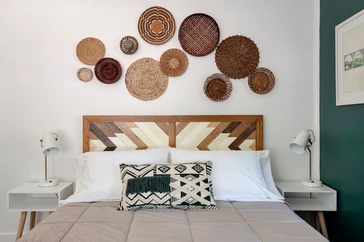 The first of the queen bedrooms features boho decor, including chevron wood inlay on the headboard, handmade by host Jess, and original artwork by a local artist in St. Petersburg.