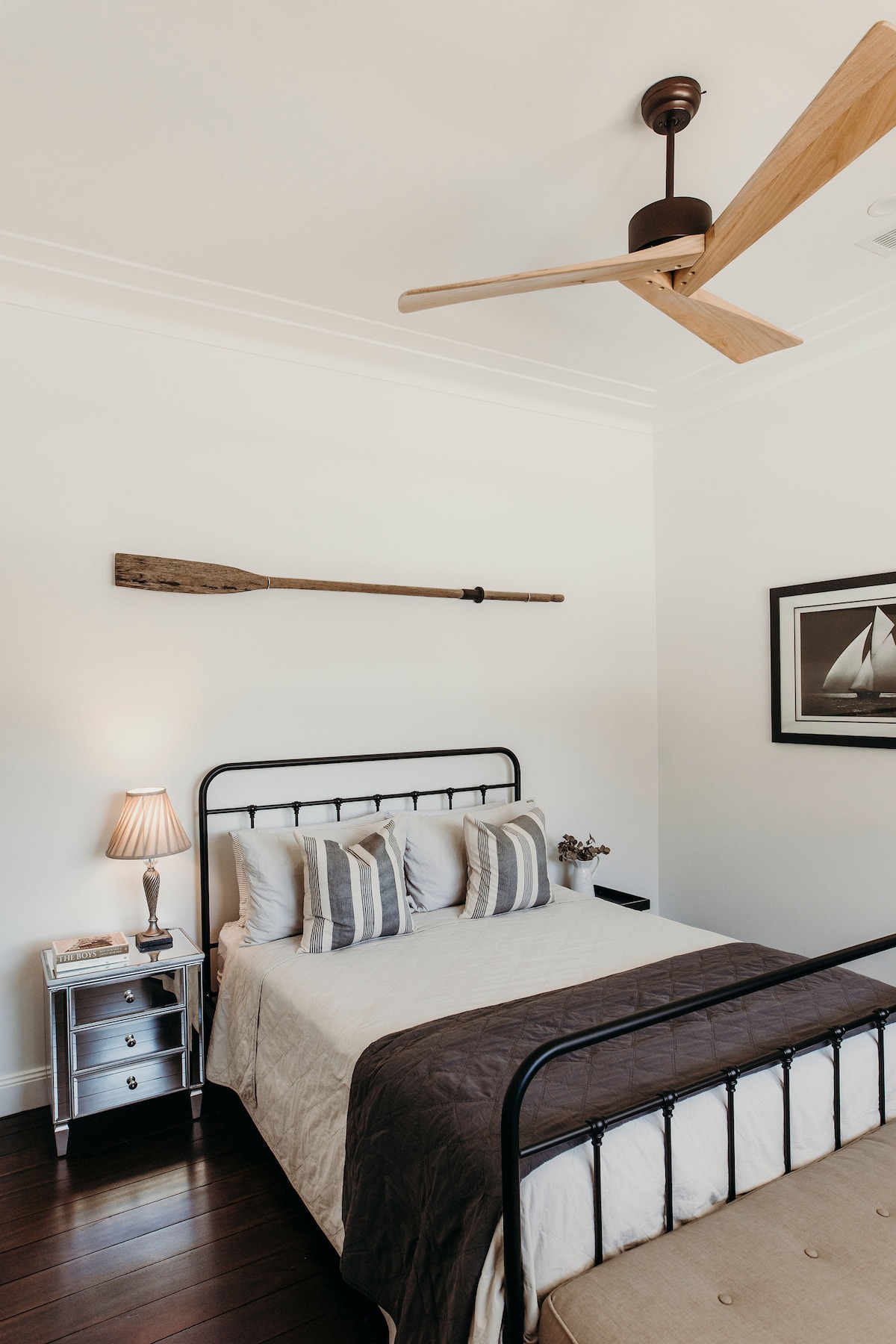 Bedroom one with queen size black iron bed, quality linen, AH Beard mattress, old ships oar and Early Settler wood ceiling fan.