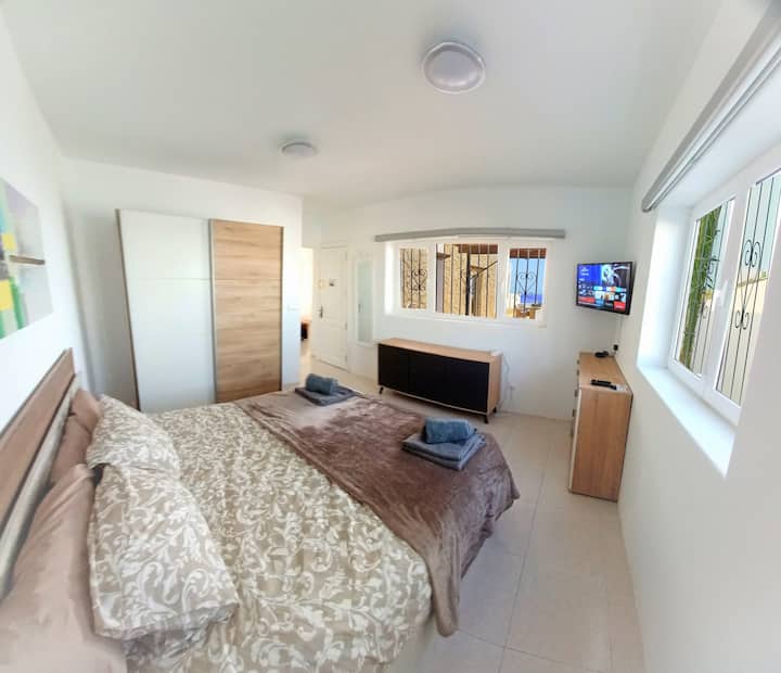 Спалня с изглед към морето и телевизор