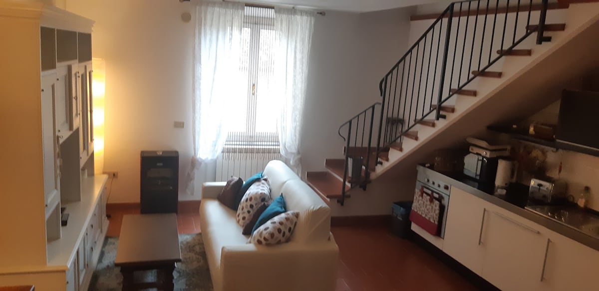 غرفة معيشة بسرير أريكة ونافذة تواجه الفناء الداخلي الصغير للدير السابق 