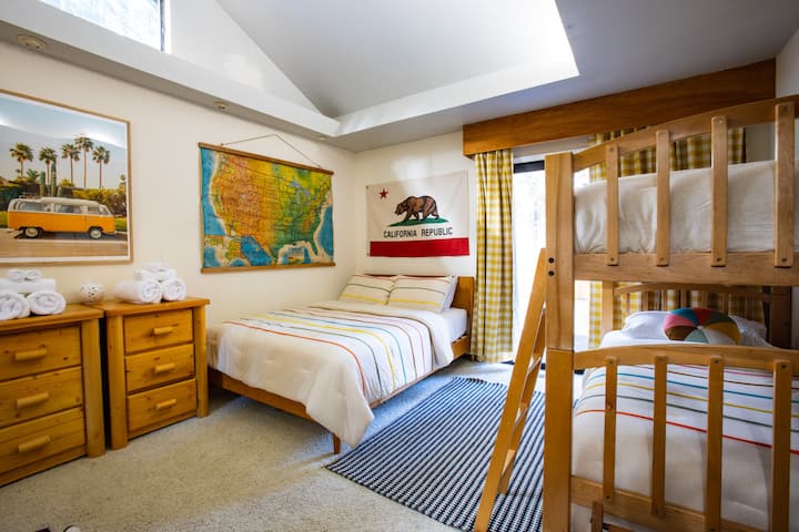 Bunk room includes one Queen Bed, 2 - Twin Bunks, and USB/USB-c Ports and access to the backyard. Crib is available.