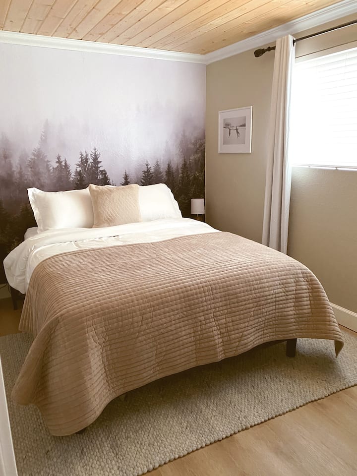 The Forest Room with a queen size bed, Smart TV, wireless phone charging station, white noise machine, desk and cozy furniture.