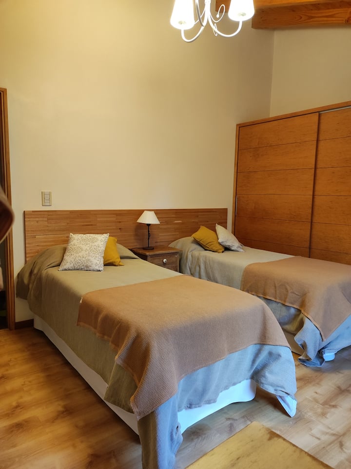 חדר שינה לשני אורחים המשקיפים על הגינה האחורית, עם כיריים גז מתנדנדות ושלט גדול.