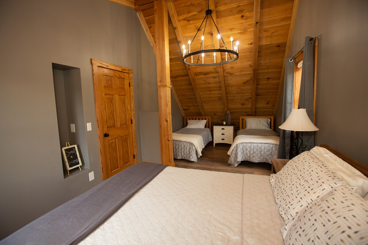 The second bedroom features a plush Queen bed and two comfortable twin beds with lamps and nightstands. Look at that gorgeous ceiling!