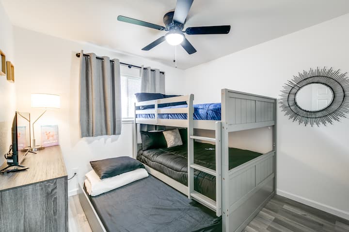 Habitación litera con cama.  Las literas son de tamaño completo y el nido es un gemelo. 
Nota: la lámpara tiene un puerto USB. 
 Perchas y TV.