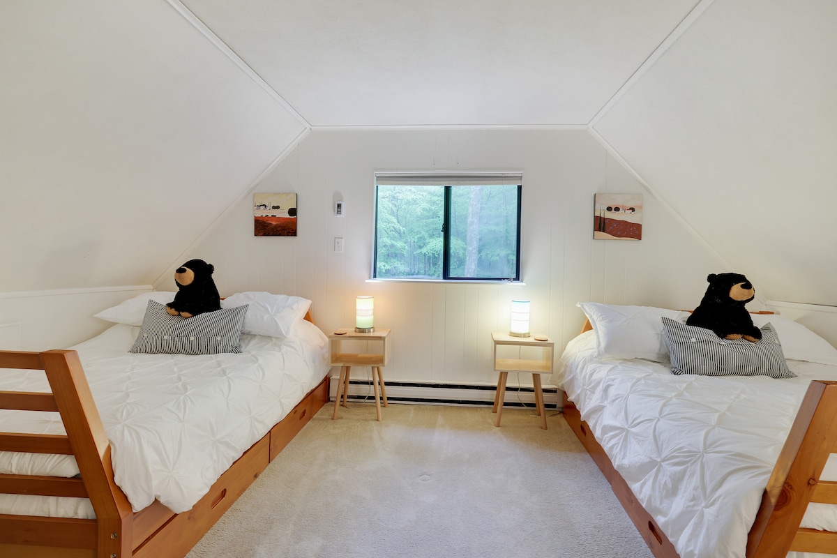 Lofti ka 2 krevate me madhësi të plotë, komodinë, raft valixhesh, stenda nate dhe një televizor