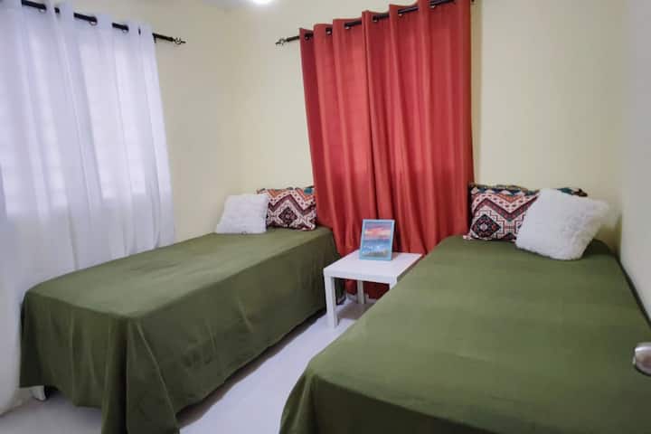 Ang berdeng kuwarto.  Dalawang twin bed na may ceiling fan, side table at malaking aparador.