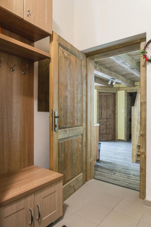 A welcoming entrance area is featured, showcasing wooden storage cabinets and a bench. A wooden door leads to a corridor with a visible staircase. The floor is tiled, and natural light illuminates the space, enhancing its inviting appearance.