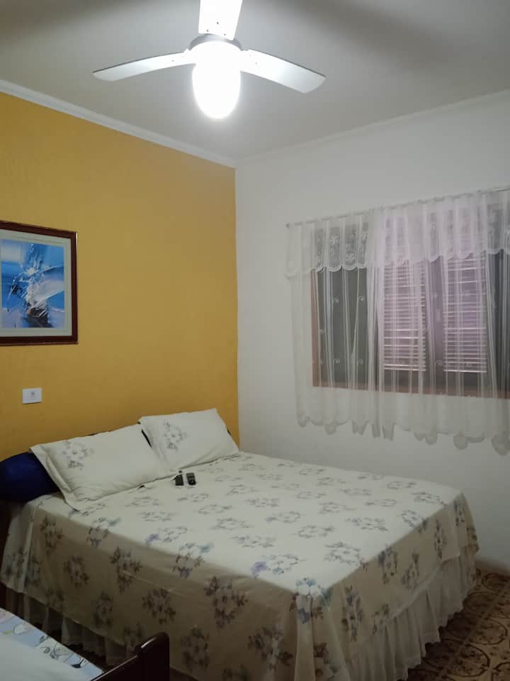 Prvá izba so stropným ventilátorom, manželskou posteľou, manželskou posteľou, televízorom a šatníkom.