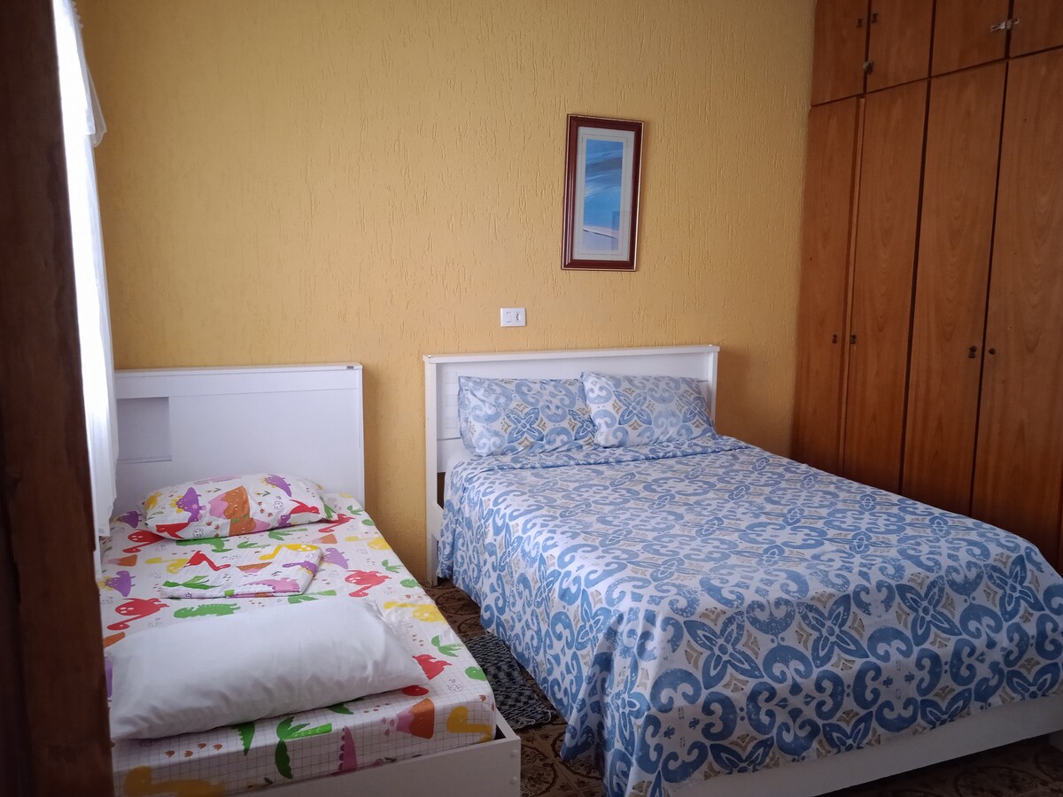 חדר שינה שני עם מאוורר תקרה, מיטה זוגית וביקאמה. טלוויזיה ומצעים.