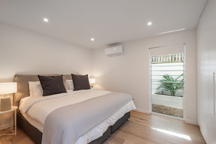 Dormitorio principal en la planta baja con aire acondicionado, luz natural, ropa de cama de calidad y fácil acceso a la planta inferior.