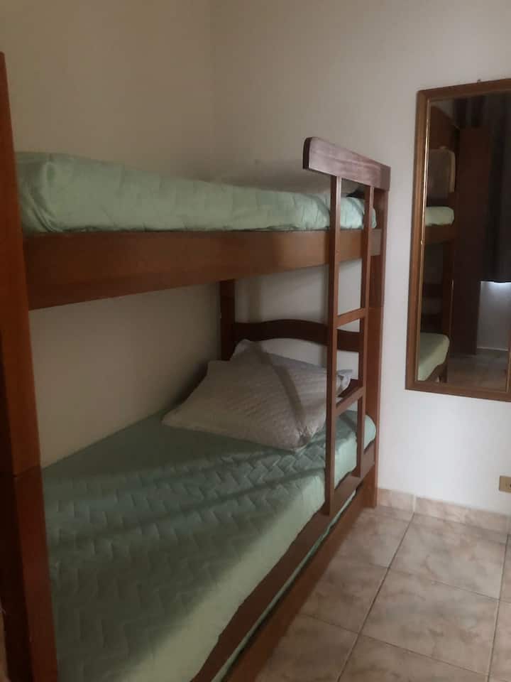 Jednolôžkový apartmán s trojicou, zrkadlom, šatníkom, malou poličkou, televízorom, malou komodou a tienidlom.