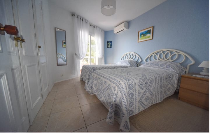 Dormitorio 2, con camas individuales, grandes armarios empotrados, aire acondicionado o calefacción en invierno. Puertas correderas del patio al balcón exterior con vistas al mar.