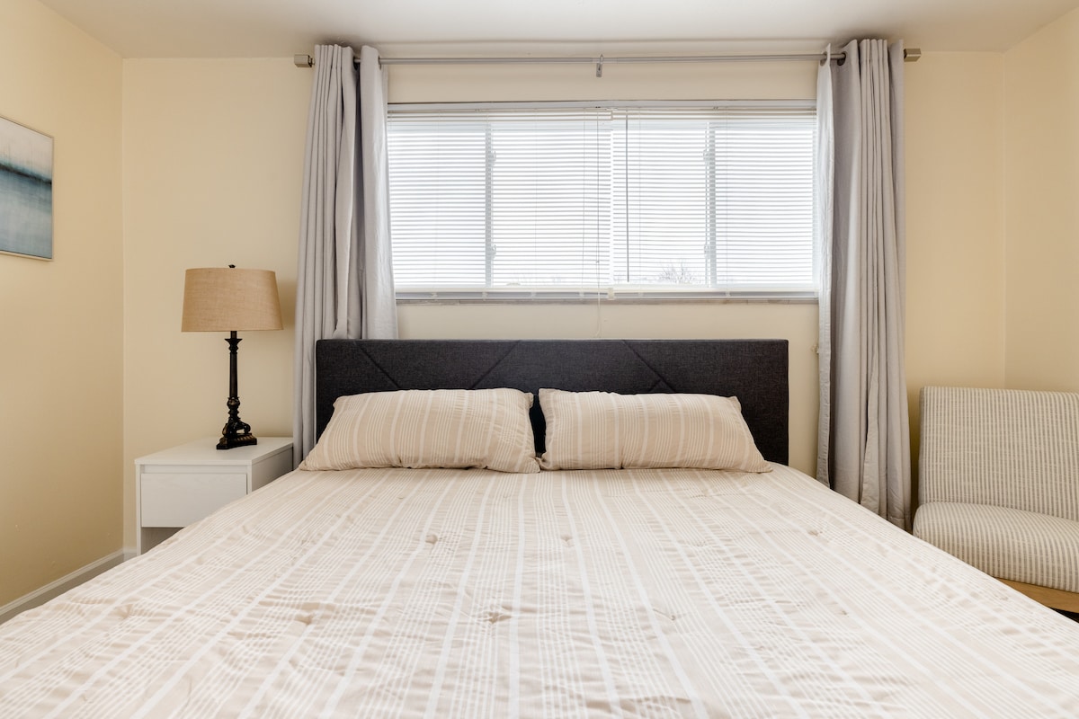 Hauptschlafzimmer mit Kingsize-Kissen und King-Memory-Schaumstoffmatratze von Casper mit 100 % Baumwollbettwäsche.  Komfortabler Slipper-Sessel in der Ecke und Ganzkörperspiegel an der Wand, um sich auf einen Abend in der Stadt vorzubereiten.