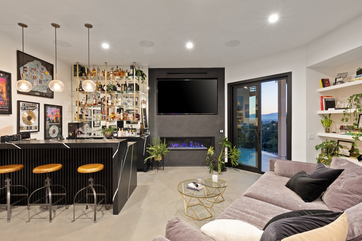 volledige bar en entertainmentruimte met tv, geluidsinstallatie en open haard met toegang tot zwembad en buitenvermaakruimte en bank ter grootte van een tweepersoonsbed