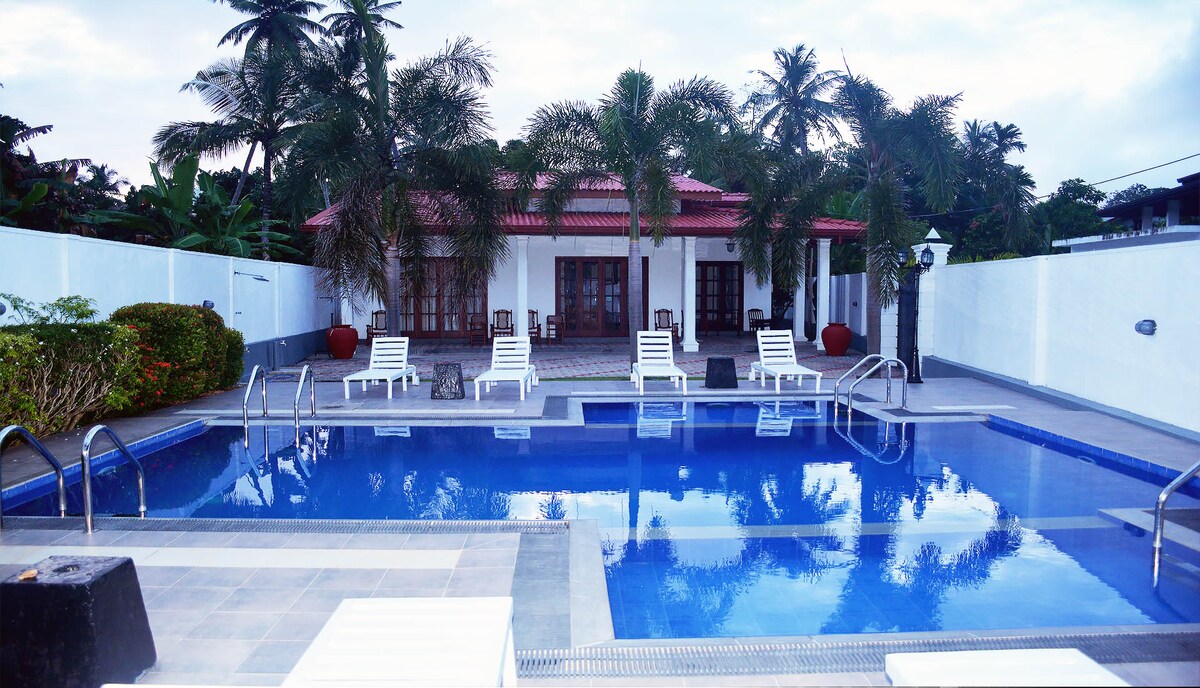 A private swimming pool is surrounded by tropical palm trees and lounge chairs. The patio area features a spacious layout, with a building visible in the background. The serene setting offers a tranquil retreat, ideal for relaxation.