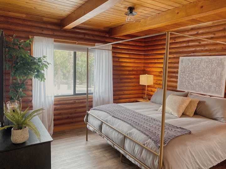 Las paredes de madera originales calientan el gran dormitorio principal que incluye persianas oscuras en ambas ventanas.