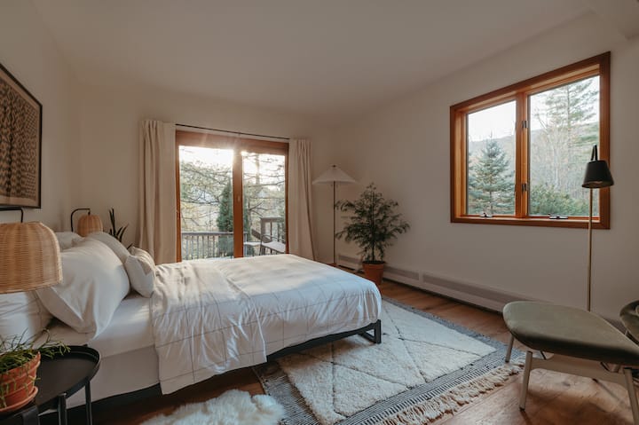 Bedroom 1 - main floor. Queen-sized bed, Blu Dot velvet lounge chair/ottoman, and deck outside. Luxe Brooklinen sheets on all beds.