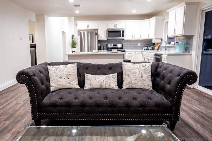 舒适的起居空间，配有簇绒沙发、玻璃咖啡桌和充满活力的地毯。 享受白砖壁炉、大电视、PS4和游戏带来的温暖，所有这些都与现代化的厨房无缝衔接，让家人尽情享受乐趣和放松。