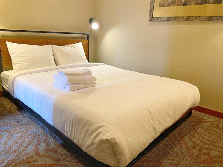 Una cama tamaño queen que te invita a relajarte y recargar energías con estilo. Esto se encuentra en un estudio con una puerta y sin ventana.