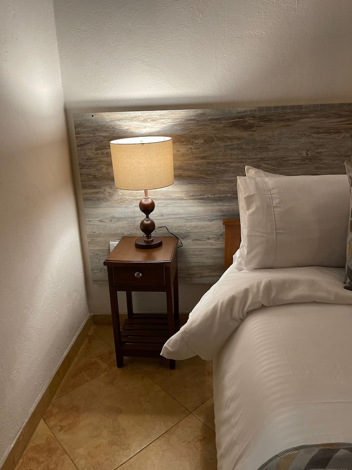 Habitación principal con baño privado con lencería hotelera, dos lamparas muy cómoda para un descanso placentero 5 almohadas