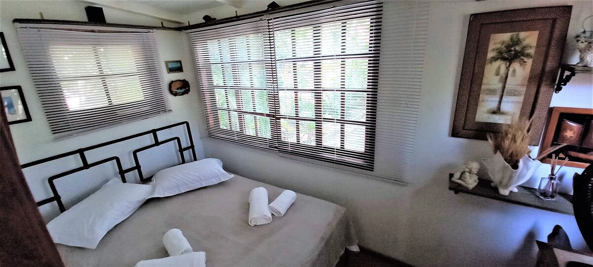 Dormitorio en planta baja. Acogedor, encantador y rodeado de jardines. Los dormitorios, tanto en la planta baja como en la suite, tienen cortinas opacas en al menos una ventana.
