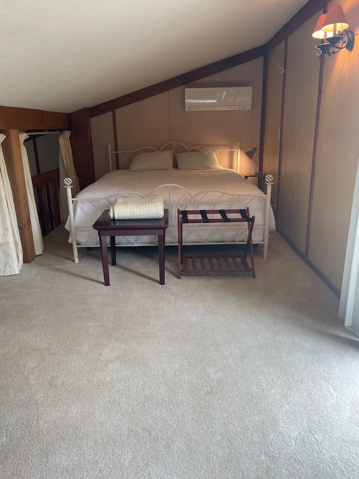 Upstairs loft room with king sized bed and wall AC/Heating unit. Patio door to second story sun deck located here. 