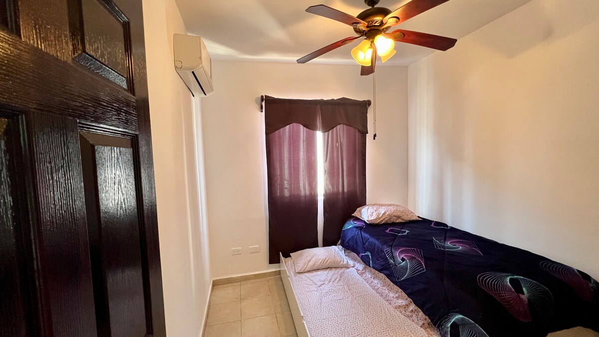 Chambre 2. Comprend 2 lits simples (1 d'entre eux est un lit kangourou), dispose d'un ventilateur de plafond, air conditionné chaud et froid, placard avec crochets et couvertures supplémentaires.