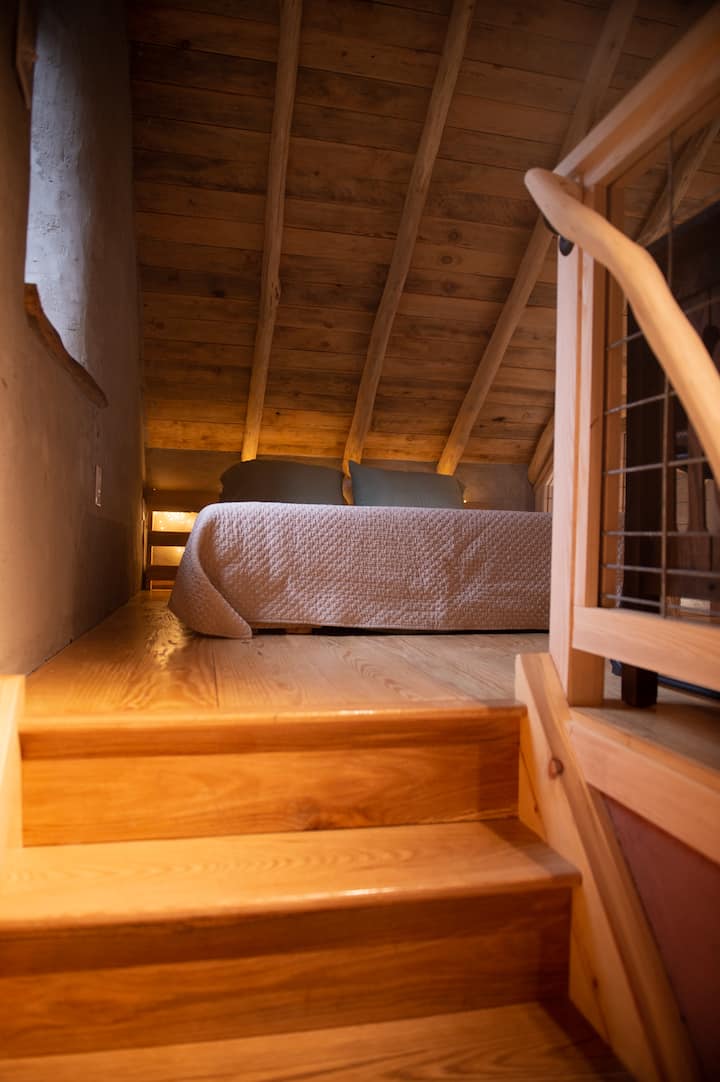View from the landing as you head to the loft. The all-natural queen bed sits on a raised bed frame.