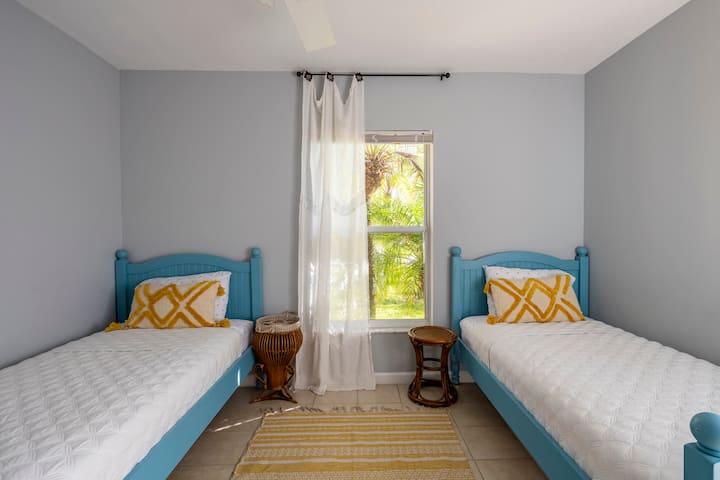 Chambre lumineuse et aérée avec deux lits jumeaux. Les deux fenêtres donnent sur des jardins avec des plantes tropicales, des cocotiers et des palmiers. Des stores occultants sont disponibles pour ceux qui préfèrent ne pas être réveillés par le soleil. 