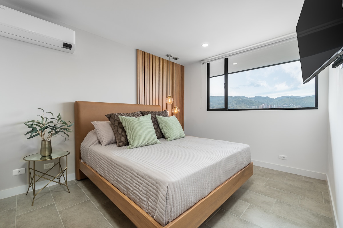 מיטת קווין סייז עם מזגן, טלוויזיה חכמה וחדר רחצה פרטי וארון.