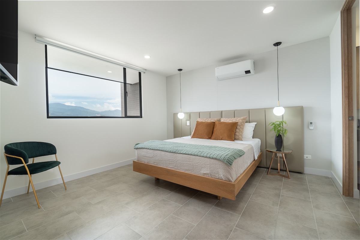 מיטת קווין סייז עם מזגן, טלוויזיה חכמה וחדר רחצה פרטי וארון.