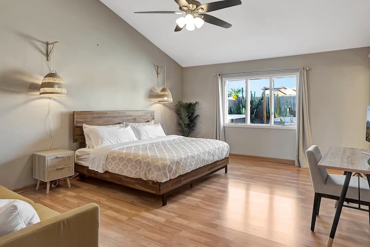 Experience the beauty of bohemian design in our master bedroom, featuring a king size bed, vaulted ceiling, and a view of our botanical garden filled with cacti and succulents