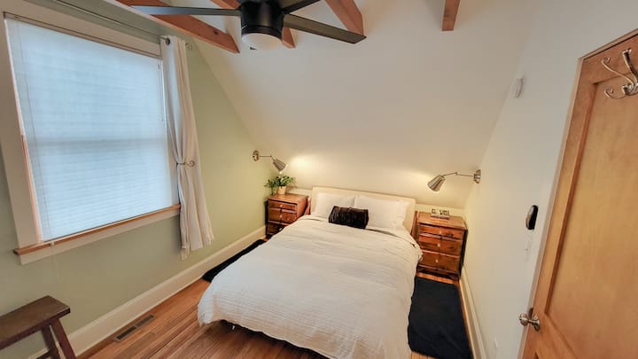 Dormitorio con cama tamaño queen, apliques junto a la cama, ventilador de techo, ventana y amplio espacio para colgar ropa o almacenar dentro de una cómoda escondida dentro del armario. 