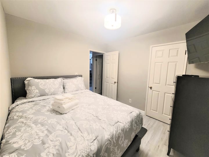 DOWNSTAIRS BEDROOM WITH QUEEN BED & TV
