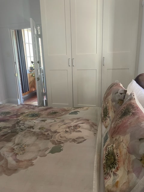 غرفة نوم بسرير بحجم كبير وخزانات على الجدار المقابل أيضًا