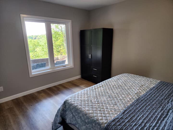 Birch Bark Retreat.  Брачен кревет, поглед на двор и езеро.  Во оваа соба има и работно биро ако планирате да работите на далечина за време на престојот или само сакате да разговарате за е-поштата.