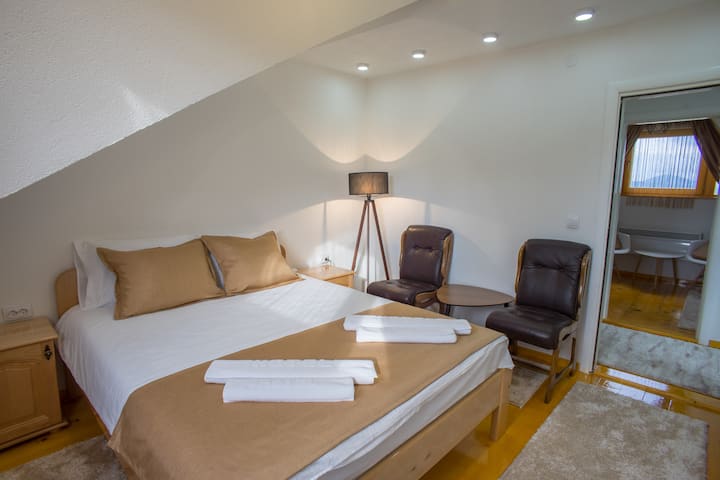 Spálňa s veľkou manželskou posteľou vyrobenou z prírodného dreva s pohodlným matracom pre pohodlnú a relaxačnú dovolenku a spanie