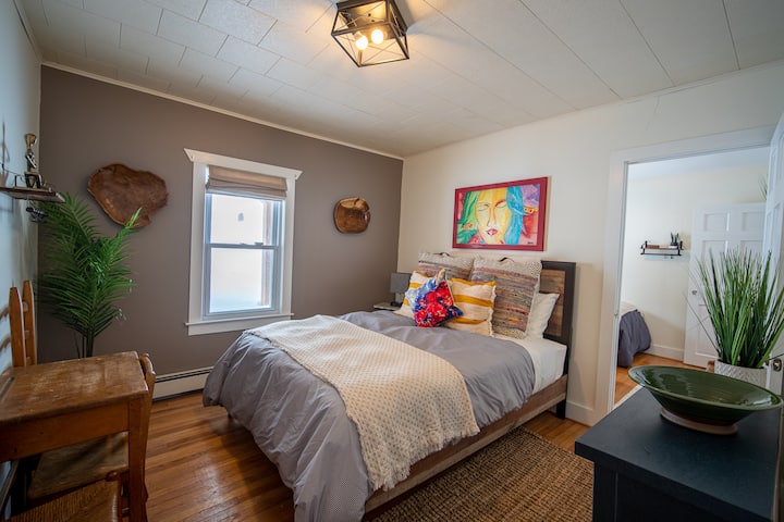 "Habitación Bali": ubicada en el primer  piso y recuerda a los días en la naturaleza balinesa, tiene una cama queen y también colinda con la "HABITACIÓN DE ESQUÍ #6" con 2 camas individuales y perfecta para una familia. Tiene una estación de carga junto a la cama y un escritorio portátil.