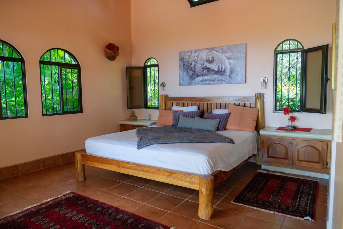 Dormitorio grande de 42 metros cuadrados con cama ortopédica tamaño king, el sistema de aire acondicionado inversor consciente de la energía, ventilador de techo y regulable junto a las luces. También hay un escritorio y una silla, todos hechos de madera recuperada.