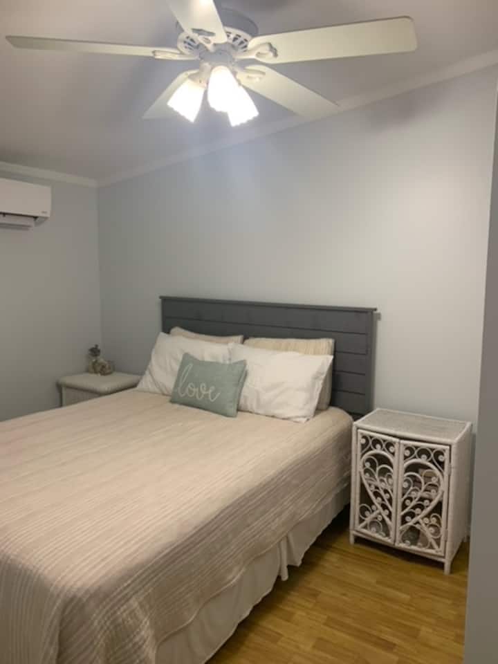 Bedroom two - queen bed, two small bedside tables (one with drawers), ceiling fan, and closet. 