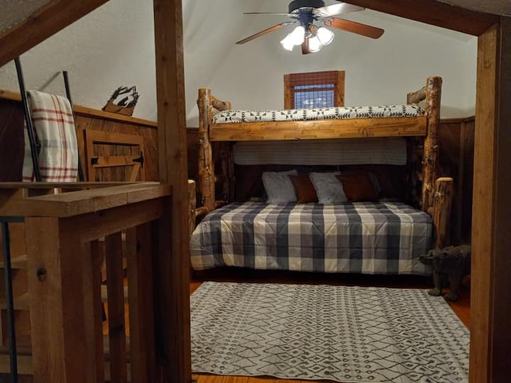 Rustic bunk beds with a Twin XL at the top and a queen on the bottom. A privacy screen is available for use between the bedroom and the loft area. 