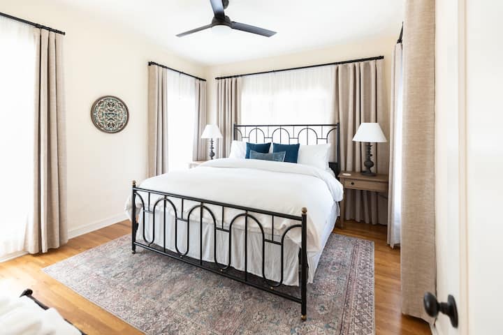 Ზემოთ საძინებელი, რომელშიც არის საწოლი „King Saatva“, ლუქს-კლასის 640 ‑ იანი თეთრეული და უშუქო ფარდები.