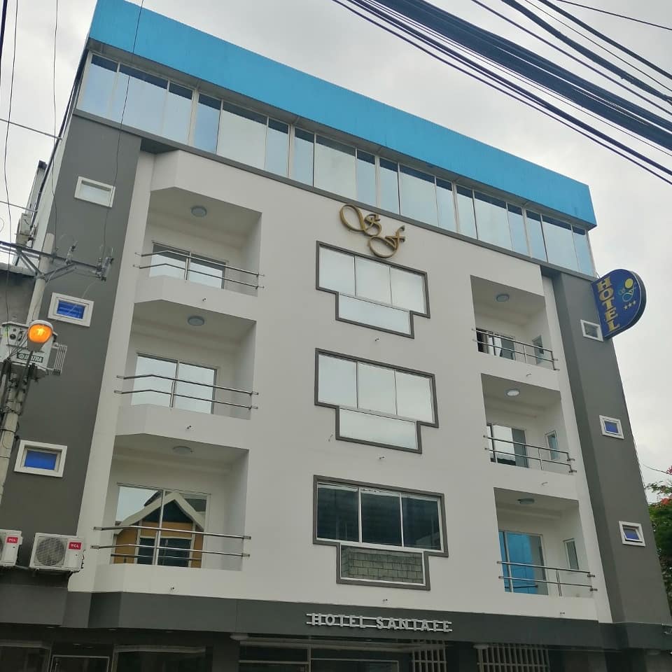 The exterior of the building presents a modern design with a clean white facade complemented by blue accents. Large windows are featured on each floor, providing natural light to the interior. The establishment's name is displayed prominently at the top.