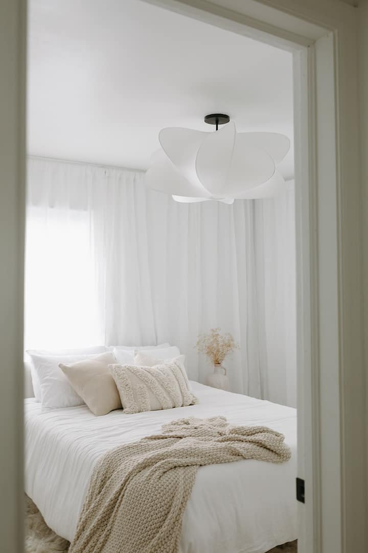 One of two main floor bedrooms, with a queen size green tea mattress designed with layered textures in mind to create a cozy feel to snuggle in. Blackout blinds are hiding under the floor to ceiling curtains. 