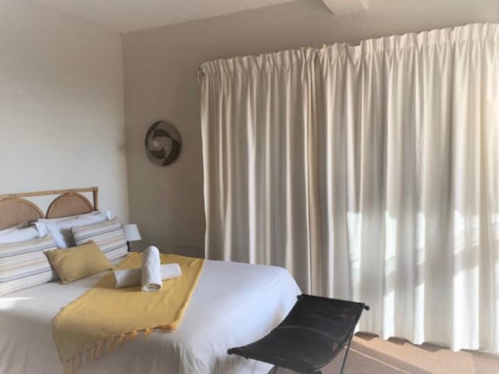 Საძინებლის ფლიგელი კარით ვერანდაზე, საიდანაც ოკეანის ხედები იშლება.