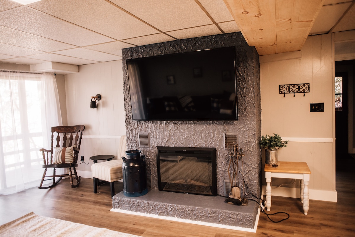 Lower level living area, featuring 65" smart TV, electric fireplace, and plenty of space to relax and enjoy with your friends.