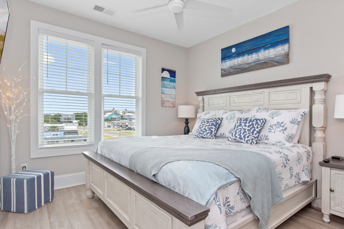 Ëndrrat bregdetare të presin!  Kjo dhomë gjumi "king" për vizitorët ka një set elegant të dhomës së gjumit IFD Stone dhe një temë qetësuese plazhi të ndriçuar nga hëna.