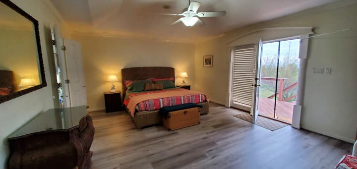 מיטת קינג סייז בחדר השינה הראשי עם גישה למרפסת ונוף למפרץ.