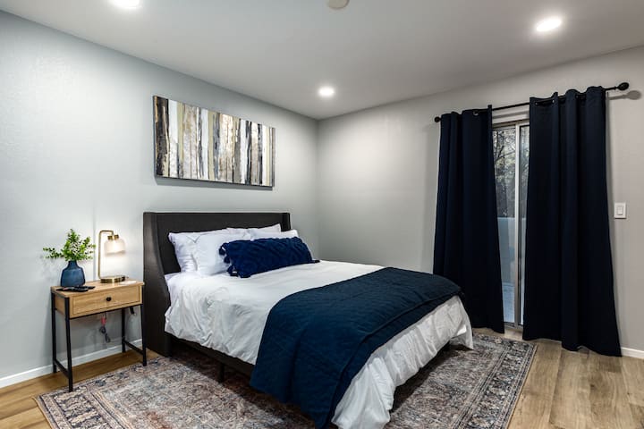 Slaapkamer 1 met queensize zilver 11,75" medium stevig matras en Casper Essential Kussens. 55" Sony televisie met meer dan150 kanalen en alle lokale zenders. Toegang tot alle streamingapps. Schuifregelaar met toegang tot balkon boven.